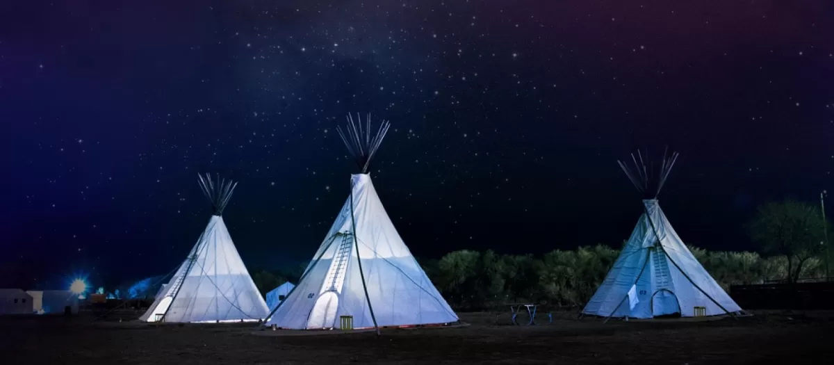 Teepees glowing under athe night moonlight